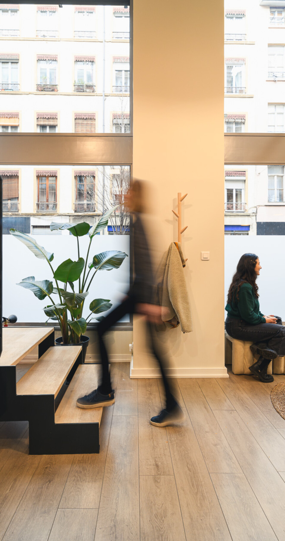 Intérieur moderne avec personnes discutant, escalier visible.